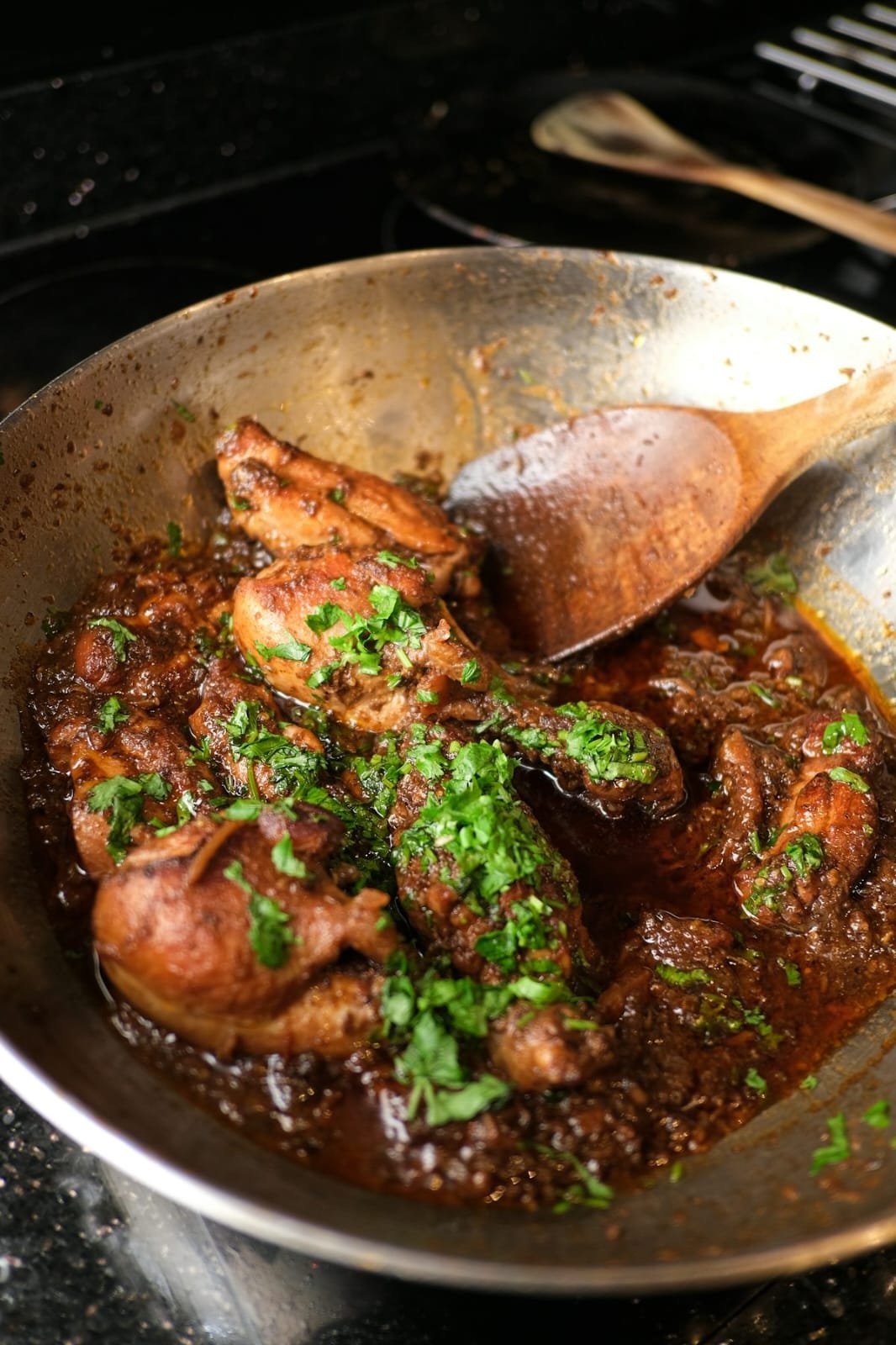 Cooking pan of slow-cooked braised meat curry with wooden ladle