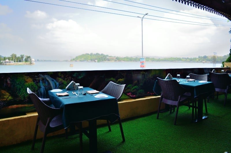 Dining table with green linens overlooking Lake Pichola water line