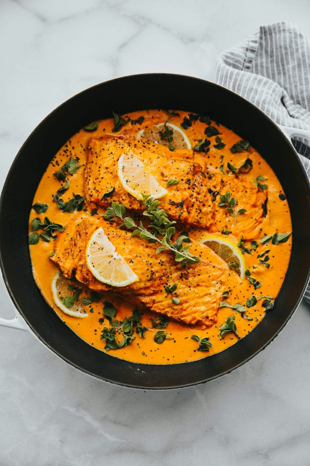 Cast iron skillet with creamy golden curry garnished with lemon slices