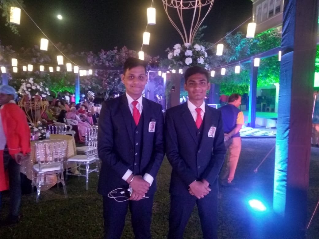 Weddings Mine hospitality directors in suits welcoming guests at evening venue