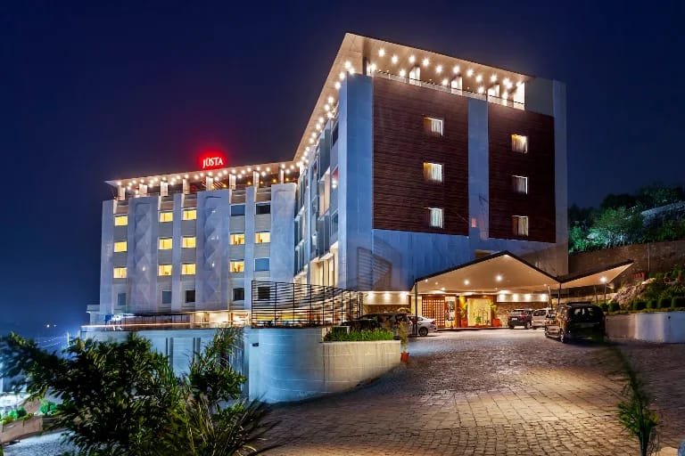 Contemporary luxury hotel facade illuminated at twilight with driveway and modern guest entrance