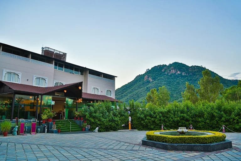 Resort courtyard fountain and guest suites overlooking green hills in Udaipur
